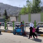 Children walking along a sidewalk in the city.