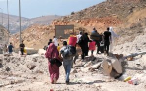 People carry their luggage as they cross the Jdeidet Yabous border into Syria on foot, as the main road between the Lebanese and Syrian sides of the border has been destroyed by an Israeli airstrike. © UNHCR/Houssam Hariri