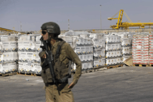 Israeli soldier with humanitarian aid packages waiting to be picked up on the Palestinian side